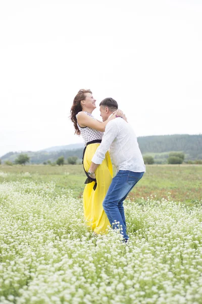 Szerelmesek férfi és a nő séta a virág mező. — Stock Fotó