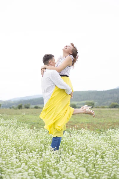 Amantes homem e mulher caminham no campo de flores . — Fotografia de Stock