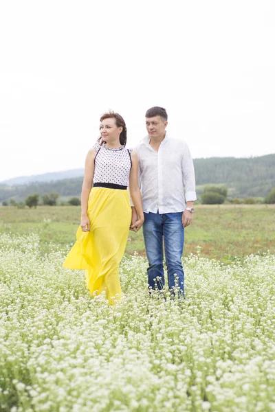 Amantes homem e mulher caminham no campo de flores . — Fotografia de Stock