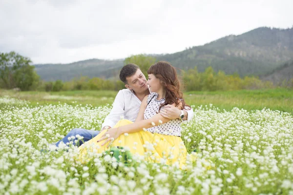 Los amantes se encuentran con hombres y mujeres en un hermoso campo de flores . — Foto de Stock