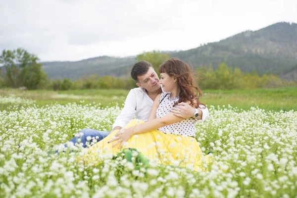 Los amantes se encuentran con hombres y mujeres en un hermoso campo de flores . — Foto de Stock