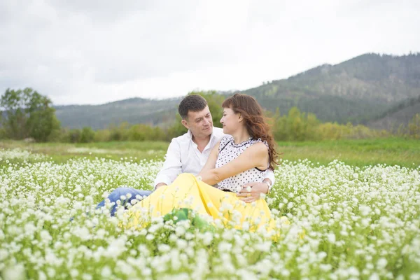 Los amantes se encuentran con hombres y mujeres en un hermoso campo de flores . — Foto de Stock