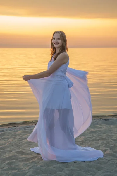 해변에 산책 긴 하얀 드레스를 입고 아름 다운 소녀. — 스톡 사진