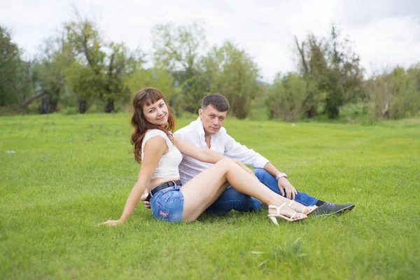 Amantes hombre y mujer sentado en la hierba verde . — Foto de Stock