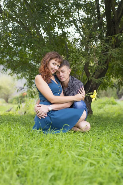 Amantes hombre y mujer sentados a la sombra de un árbol frondoso . —  Fotos de Stock