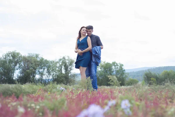 Szerelmesek férfi és a nő séta a vörös virág mező. — Stock Fotó