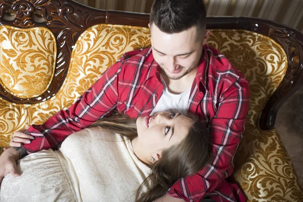 Eine junge schwangere Frau und ihr glücklicher Ehemann ruhen sich auf der Couch aus — Stockfoto