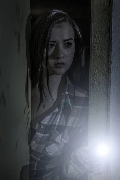 Een huilerig jong meisje kijkt uit van een donkere kamer. — Stockfoto