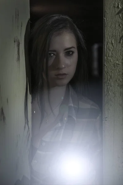 Een huilerig jong meisje kijkt uit van een donkere kamer. — Stockfoto
