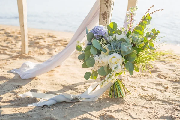 Um bouquet nupcial lindamente decorado está à mesa no fundo da água na margem de um lago — Fotografia de Stock