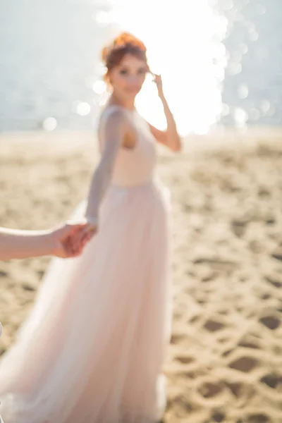 Piękne kobiety, młodej trzyma w ręce człowieka na świeżym powietrzu na plaży. Za mną. Efekt rozmycia jest tworzony dla romantyczne ramki. — Zdjęcie stockowe