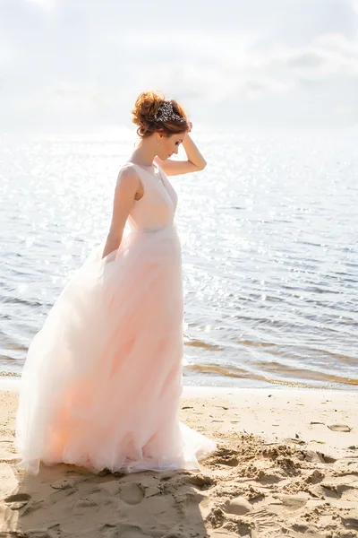 Portrait de belle mariée debout au bord de la plage au coucher du soleil — Photo