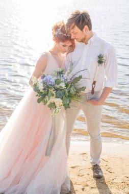 mutlu çift damat ve gelin düğün buket ile sahilde vardır