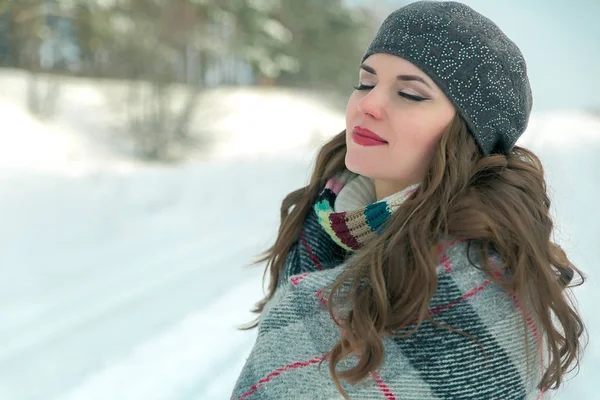 Portrait extérieur d'hiver d'une jeune fille drôle drôle positive enveloppée dans un plaid sur un fond du parc — Photo