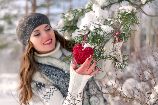 Winter outdoor portret van een leuke vrolijke positieve jong meisje met rood hart decoratie op een natuurlijke achtergrond — Stockfoto