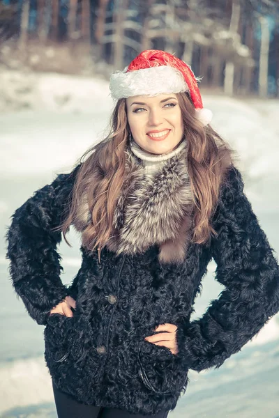 Kerst vrouw in KERSTMUTS lachend op een achtergrond van besneeuwde forest — Stockfoto