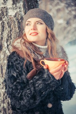 Fincan çay ile açık havada kışın tutan genç kadın