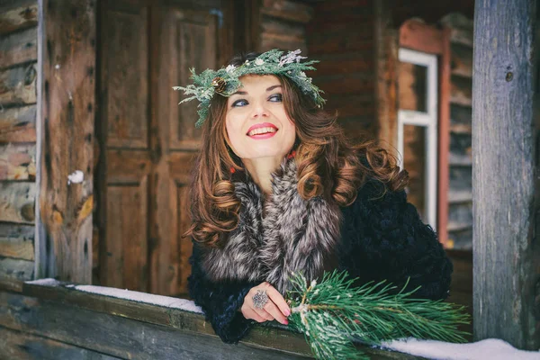Närbild porträtt av vacker brunett flicka i en krans på ett traditionellt ukrainska eller ryska hus i trä bakgrund. — Stockfoto