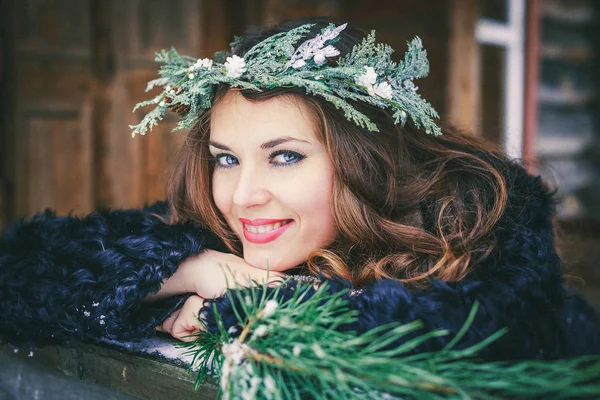美丽的黑发女孩在花圈上木制背景传统乌克兰或俄罗斯房子的特写肖像. — 图库照片