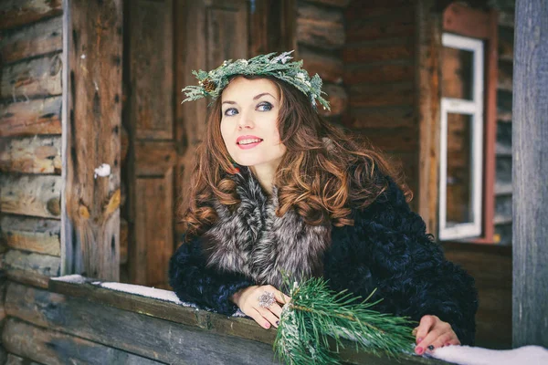 美丽的黑发女孩在花圈上木制背景传统乌克兰或俄罗斯房子的特写肖像. — 图库照片