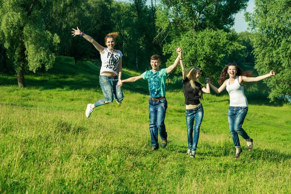 Emberek, a szabadság, a boldogság és a tizenéves koncepció. boldog baráti ugrás magas fű háttér napszemüveget visel — Stock Fotó