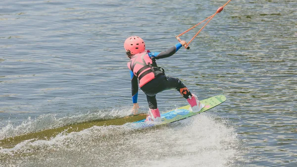 Mała dziewczynka jeździć Wakeboard. Zdjęcie z przetwarzania ziarna — Zdjęcie stockowe