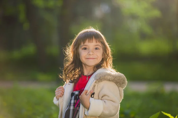 Menina bonita com cabelos longos em movimentos turbilhões e sorrisos, durante o pôr do sol no parque. O conceito de infância e liberdade . — Fotografia de Stock