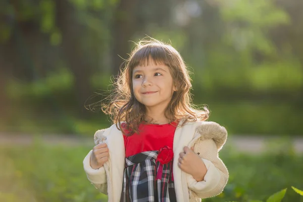 Menina bonita com cabelos longos em movimentos turbilhões e sorrisos, durante o pôr do sol no parque. O conceito de infância e liberdade . — Fotografia de Stock