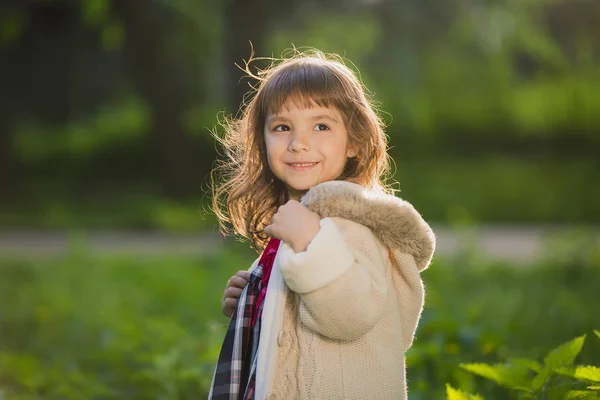 Hermosa chica con el pelo largo en movimiento gira y sonríe, durante el atardecer en el parque. El concepto de infancia y libertad . — Foto de Stock