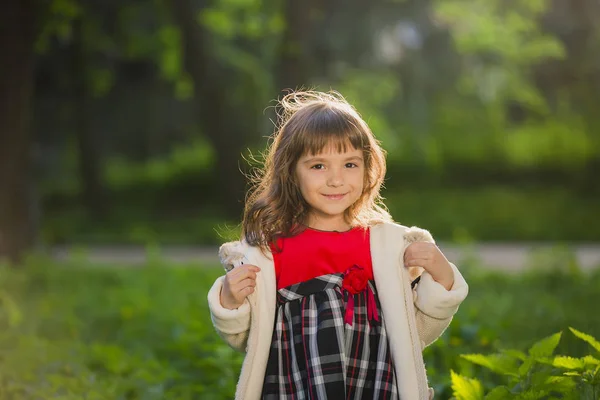 Menina bonita com cabelos longos em movimentos turbilhões e sorrisos, durante o pôr do sol no parque. O conceito de infância e liberdade . — Fotografia de Stock