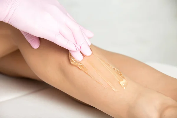 Professional cosmetician undergoing waxing procedure