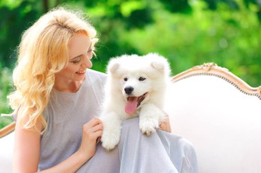Güzel genç kız ile bir yaz bahçesinde bir retro Divan kucağında beyaz bir köpek yavrusu