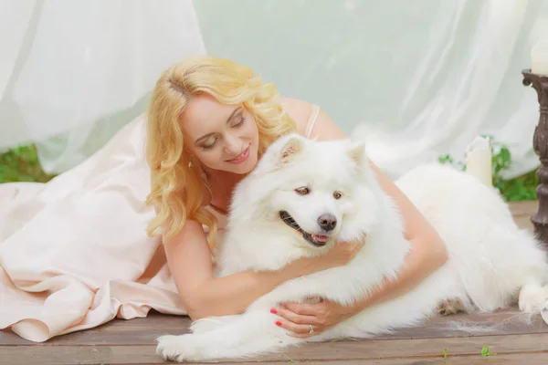 금발 여자는 손에서 하얀 강아지와 함께 야외에서 거짓말 — 스톡 사진