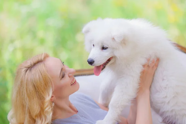 여름 정원에서 복고풍 소파에 그녀의 팔에 흰색 강아지와 함께 아름 다운 소녀 — 스톡 사진