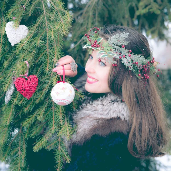Πορτρέτο του όμορφη νεαρή γυναίκα χαμογελαστή διακόσμηση χριστουγεννιάτικο δέντρο σε εξωτερικούς χώρους σε μια κρύα χειμωνιάτικη μέρα. — Φωτογραφία Αρχείου