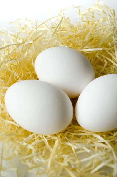 3 huevos en la paja sobre un fondo blanco — Foto de Stock