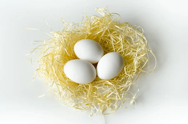 3 huevos en la paja sobre un fondo blanco — Foto de Stock