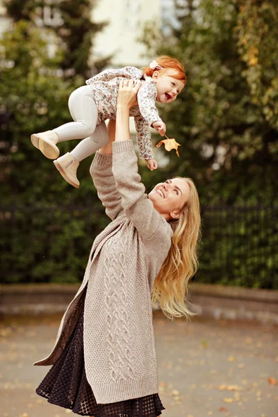 Mamá vomita una niña roja y riendo, otoño — Foto de Stock