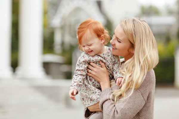 Mama omarmt zachtjes de roodharige babymeisje en lachen in de herfst — Stockfoto