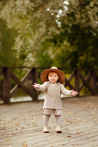 Red-haired baby girl in a hat smiling outdoors in autumn — Stock Photo, Image