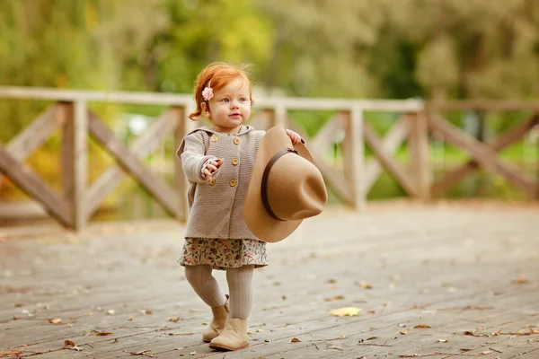 Roodharige babymeisje in een hoed glimlachend buiten in herfst — Stockfoto