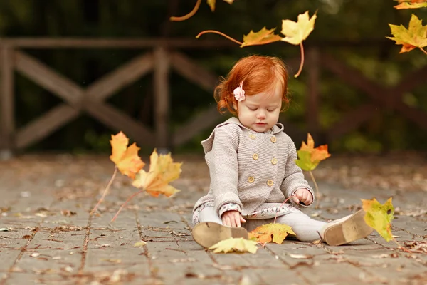 Red-haired baby girl on the background of nature and sitting in — Stock Photo, Image
