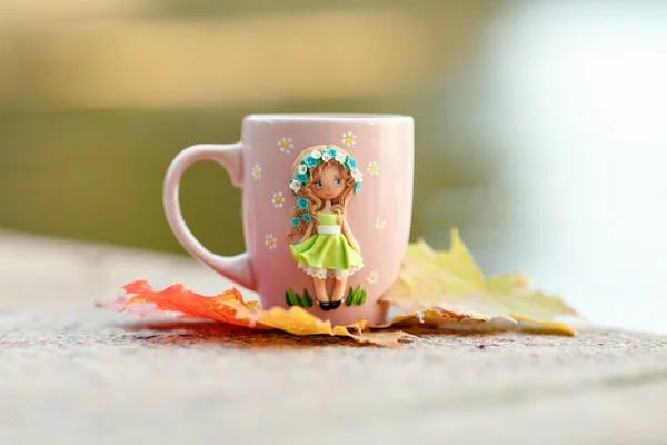 Pink mug with decorations in the form of a girl in a dress made — Stock Photo, Image