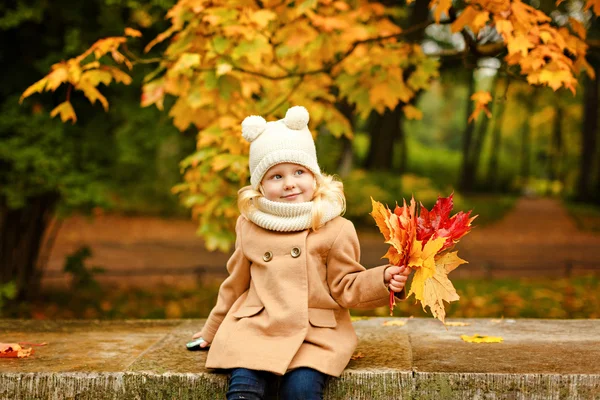 Dziewczynka Ładna w beżowy płaszcz patrząc w górę, jesienią — Zdjęcie stockowe