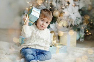 Sevimli küçük çocuk bebek Noel ağacının yanında gif ile oturuyor.