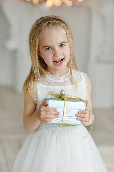 Mooi meisje zit in de buurt van een kerstboom en glimlacht ik — Stockfoto