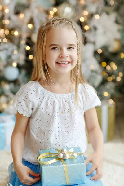 Belle petite fille assise près d'un arbre de Noël et sourit i — Photo