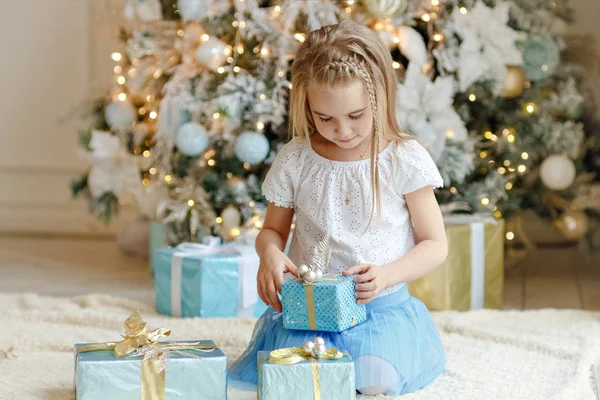Hermosa niña sentada cerca del árbol de Navidad y mirando fo — Foto de Stock