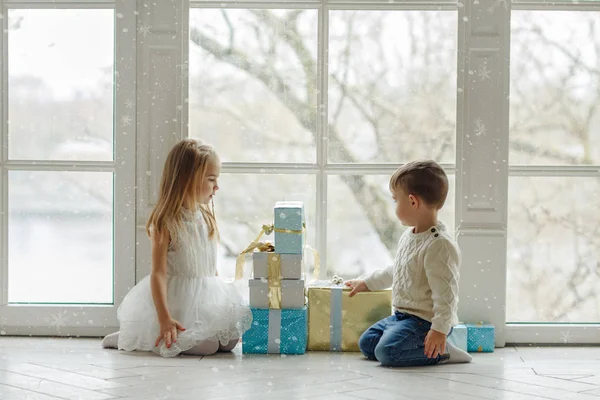 Pequeño adorable hermano y hermana sentado cerca de una gran ventana i — Foto de Stock