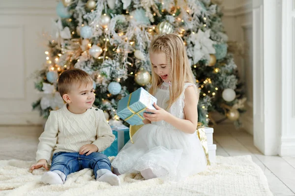 Malý roztomilý bratr a sestra sedí u vánočního stromu — Stock fotografie
